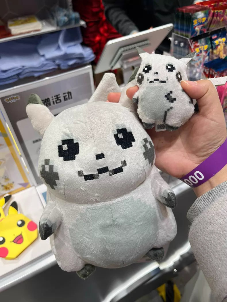 A hand holds the ZoDoll Retro 8-Bit Pikachu of Beginnings Plush Bag Clip – a Classic Chunky Pokémon 30th Anniversary Pikachu plush keychain (12cm) – next to a larger matching plush in a retail display.