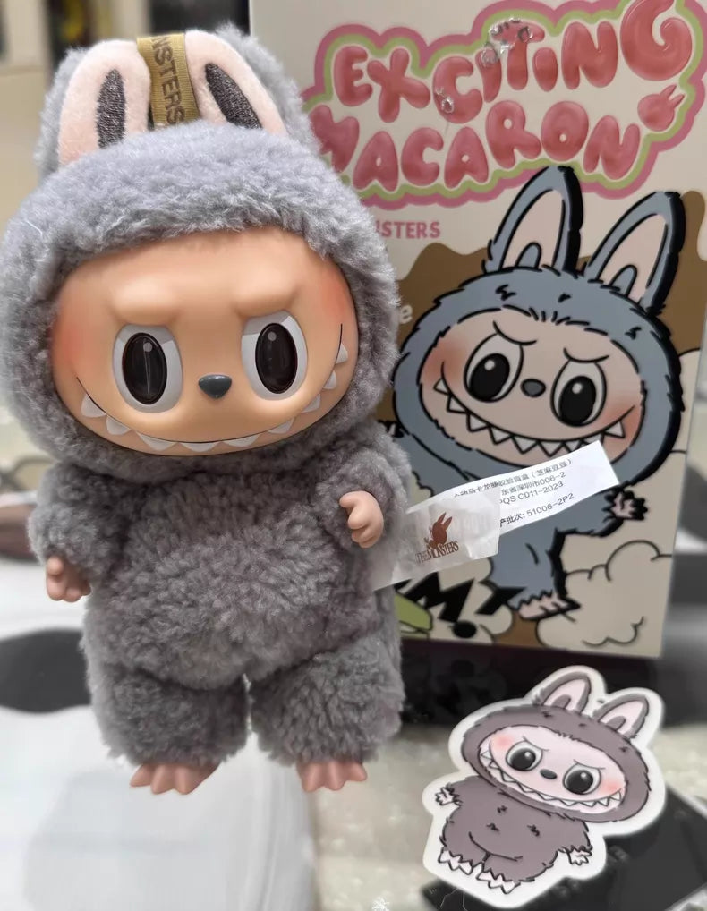 The Labubu “Sesame Bean” Plush Keychain is a POP MART collectible by Kasing Lung, featuring a wide-grinned doll in a fluffy grey bunny suit, shown with matching packaging and a sticker from the Pop Mart Sesame Bean series.