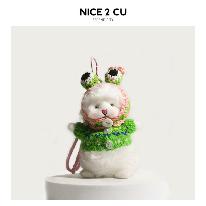 White fluffy lamb plush charm wearing a green knitted floral sweater and pink crocheted bonnet with spotted ear accents