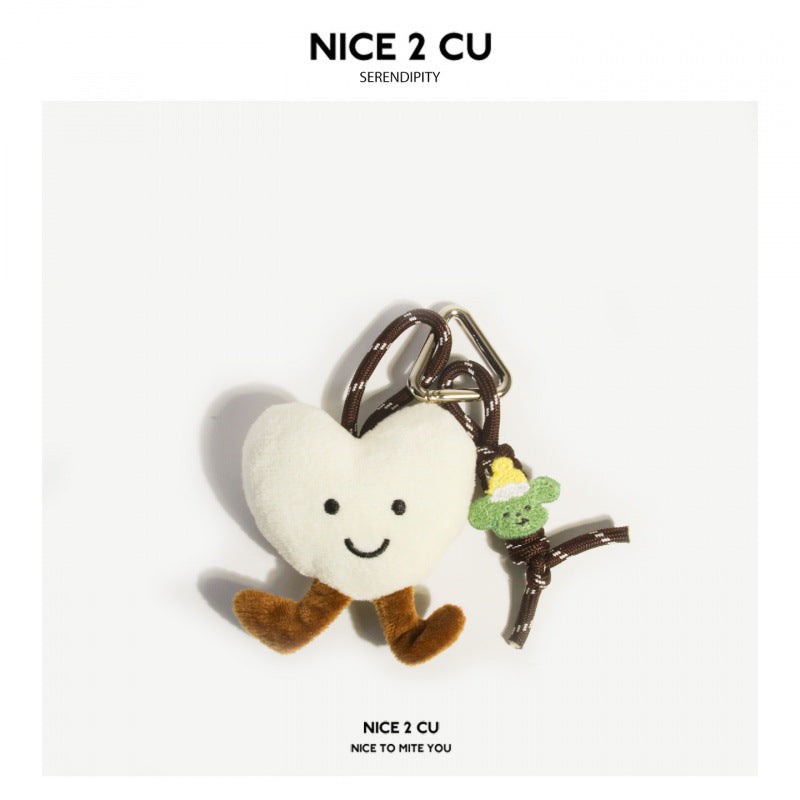 White heart-shaped plush charm with smiling face and brown legs on dark braided cord