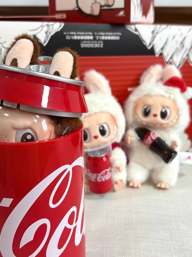 Three Pop Mart Labubu Secret Edition “Mysterious Guest – Coca‑Cola” Plush Keychain collectibles are shown with Coca‑Cola cans and bottles; one plush keychain is partly inside a large collectible Coca‑Cola can container.
