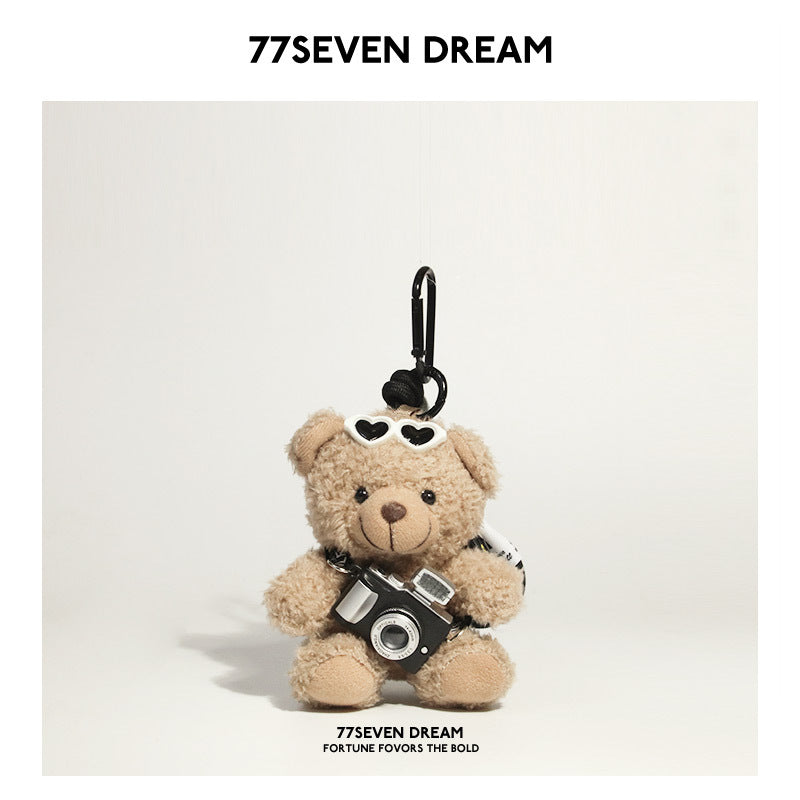 Tan bear plush keychain wearing white heart-shaped sunglasses and holding a miniature black camera