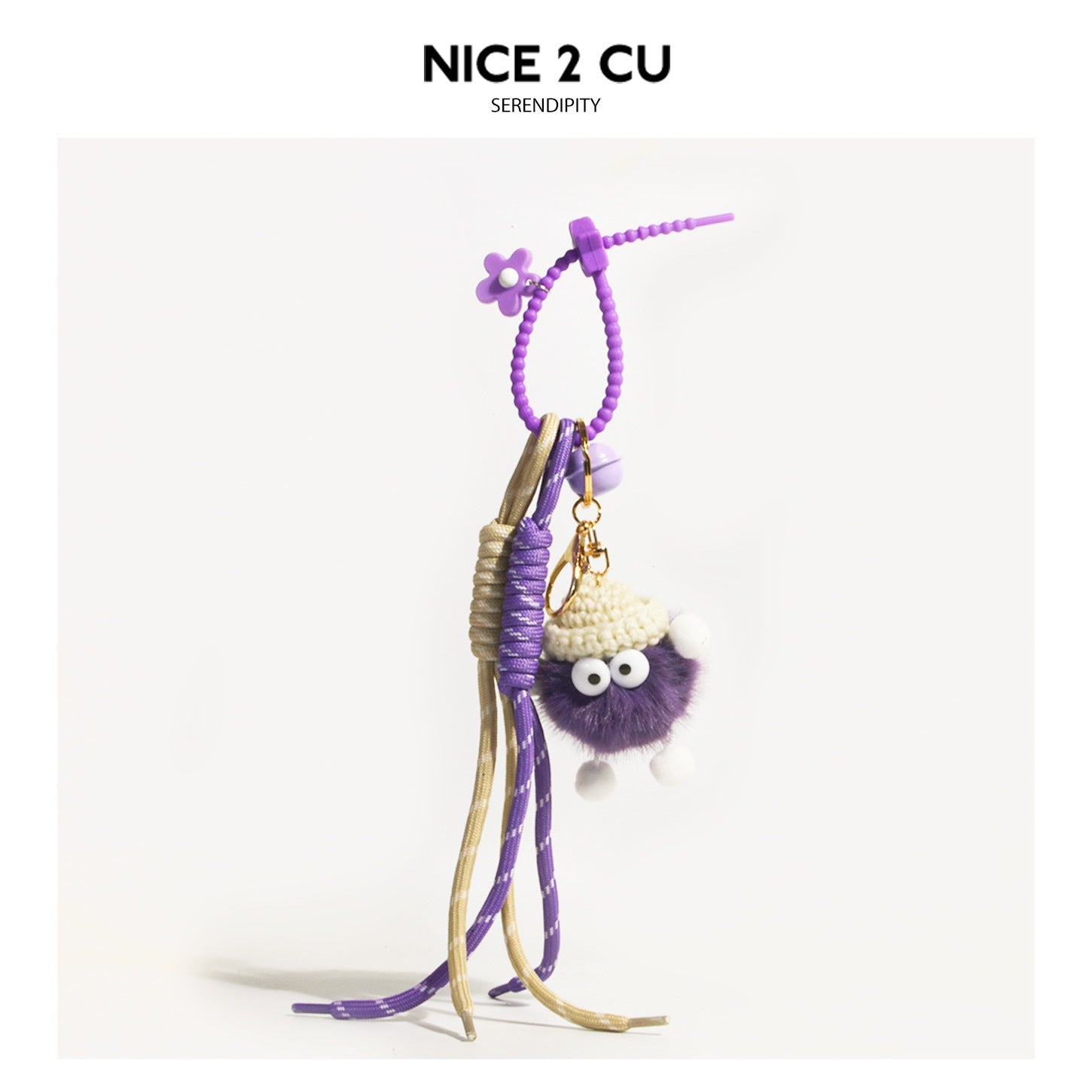 Purple fluffy round character charm with cream crocheted hat, flower bead accent, and dangling purple and beige-gold cords on