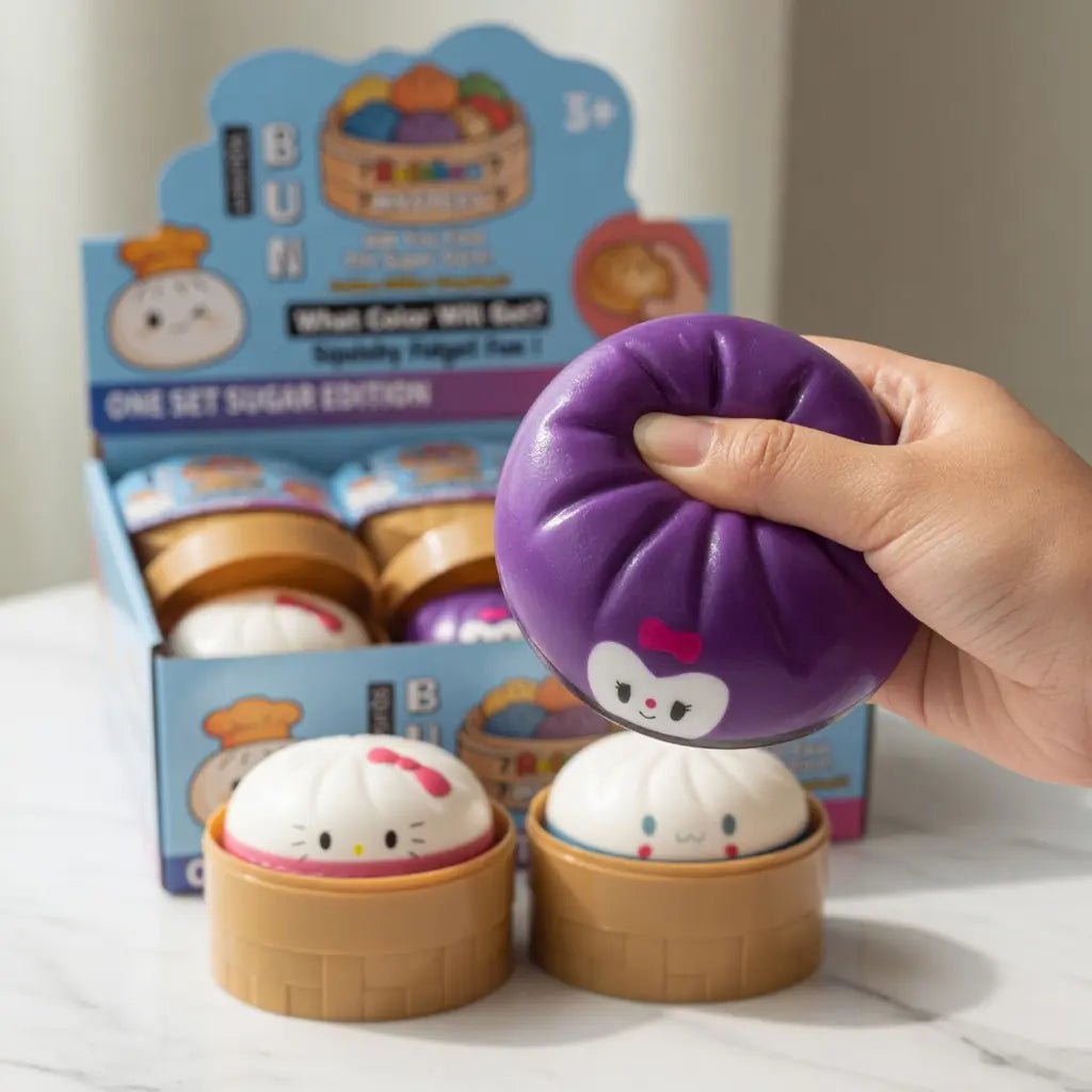 A hand squeezes a purple ZoDoll Kawaii Character Squishy Bun Fidget Toy with Steamer – Sanrio-Inspired Sugar Edition, next to two white buns in bamboo containers, all in front of the playful pink toy box.