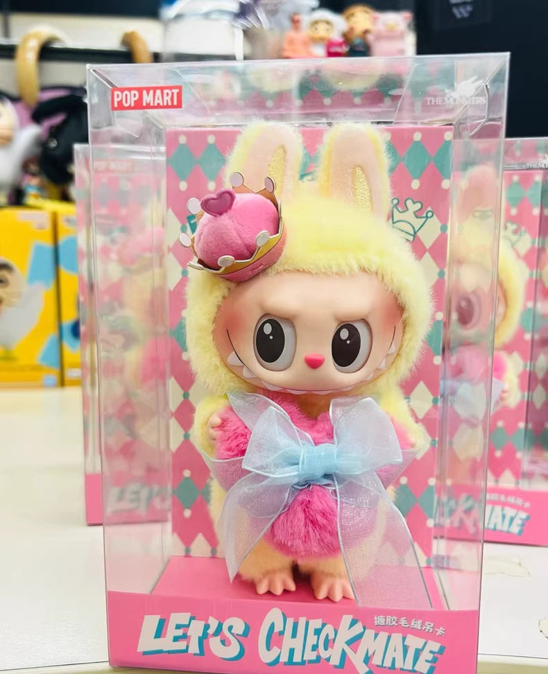 The POP MART Labubu Let’s Checkmate Series – Pink Heart Bunny Plush Vinyl Doll features Labubu in a bunny costume with a crown and blue bow, displayed in a clear LETS CHECKMATE box—an ideal collectible for fans and collectors.