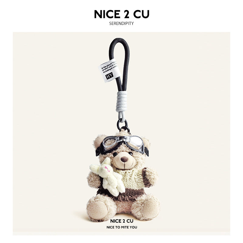 Beige plush teddy bear keychain in cream-and-brown knit sweater with aviator goggles, holding a white rabbit