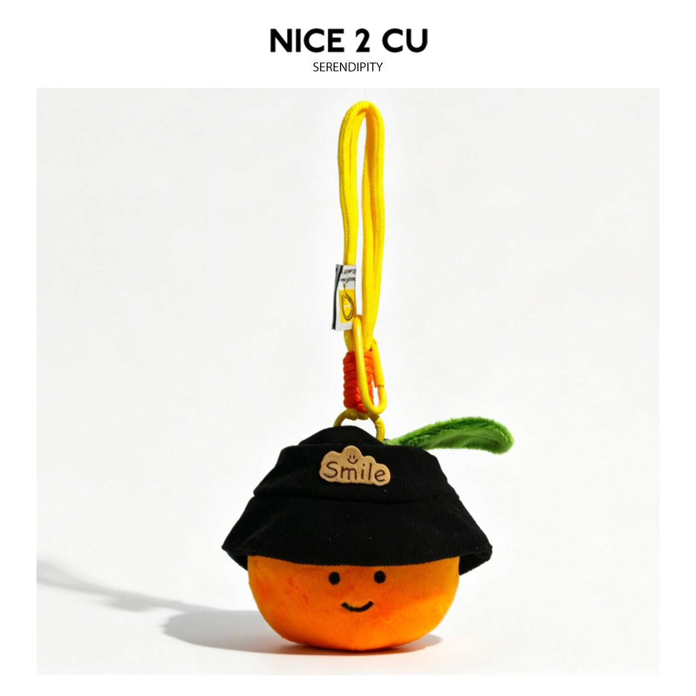 Smiling orange plush charm wearing a black bucket hat with a Smile badge and green leaf, attached to a yellow carabiner clip