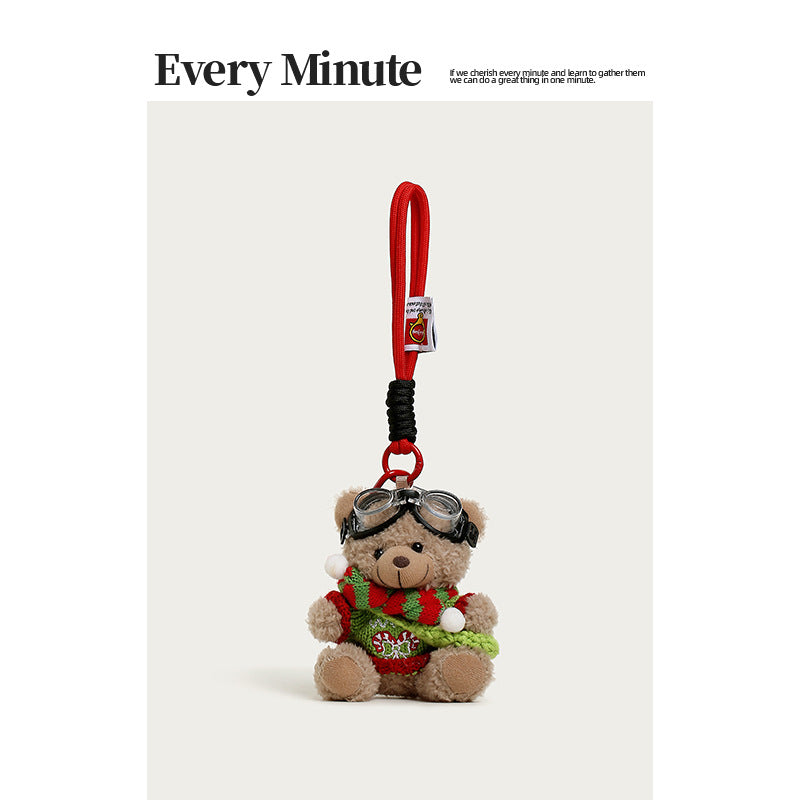 Brown plush bear charm with aviator goggles, red-and-green Christmas sweater, and candy-cane staff accessory