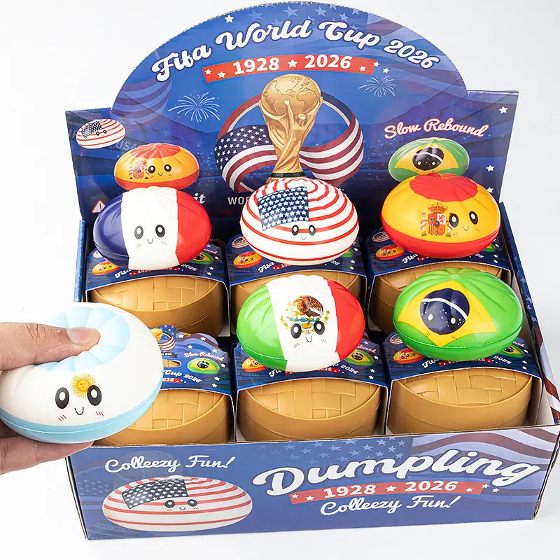The ZoDoll FIFA World Cup 2026 Squishy Dumpling Fidget Toy with Steamer features 6 country flag designs on cute dumpling-shaped stress toys, displayed on a green base. A hand squeezes one, bringing soccer-themed fun to your space.