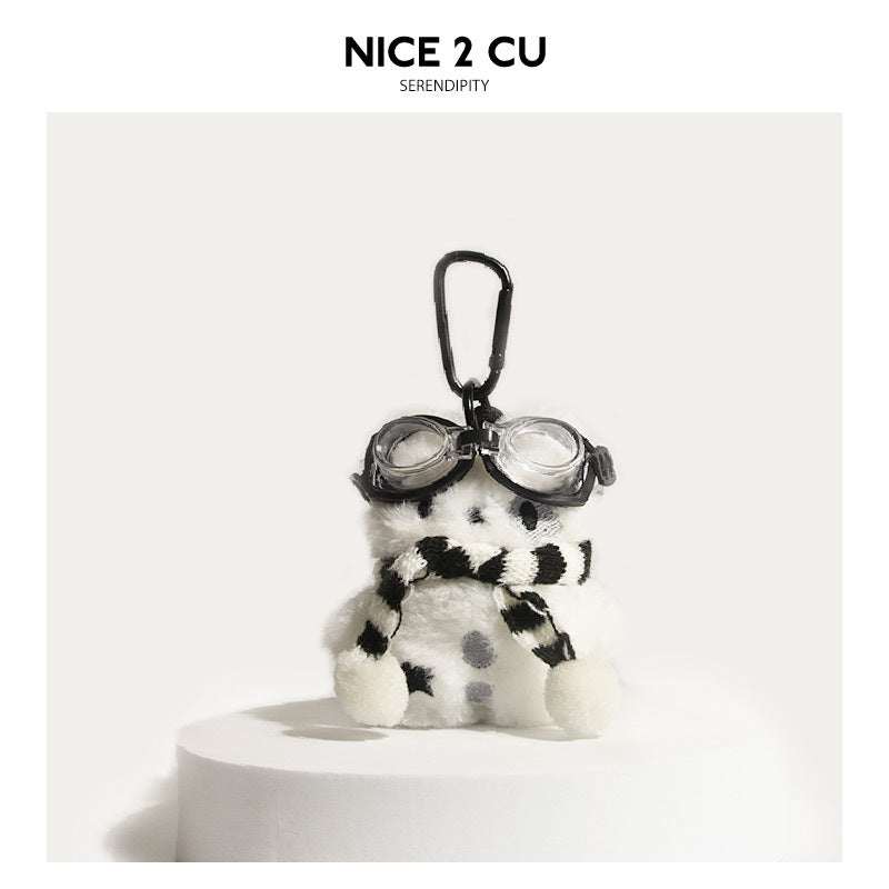 White dog plush charm with black goggles and a black-and-white striped knit scarf on a carabiner clip
