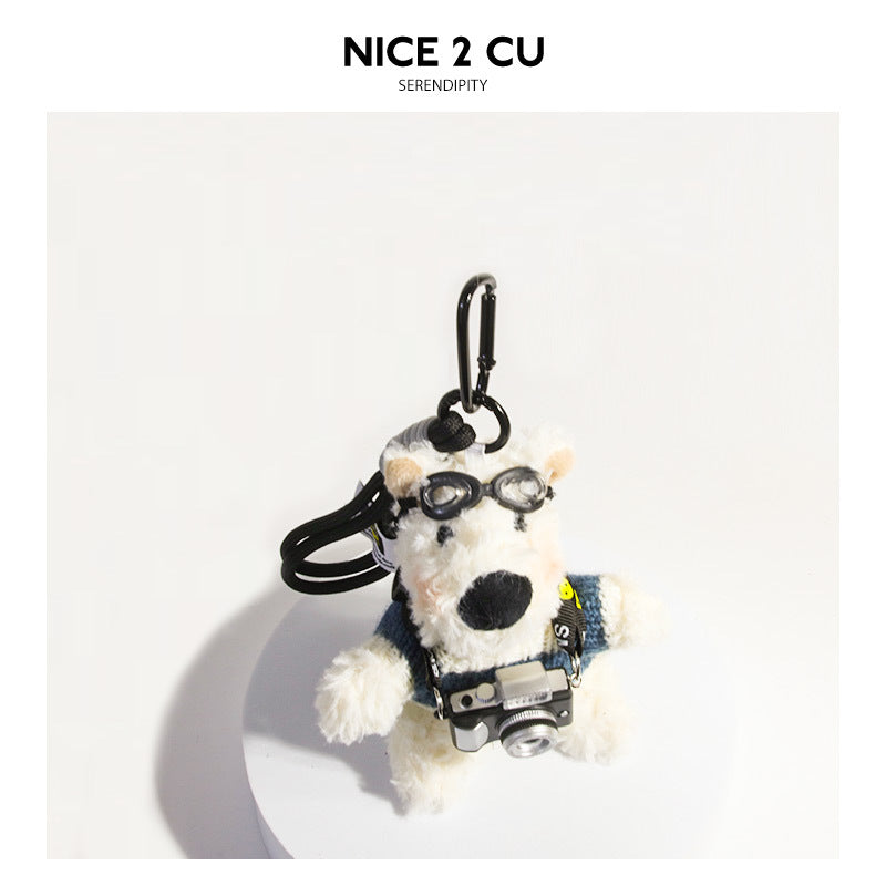 Fluffy white dog plush bag charm wearing a blue and white striped sweater with goggles and a camera on a SMILE strap