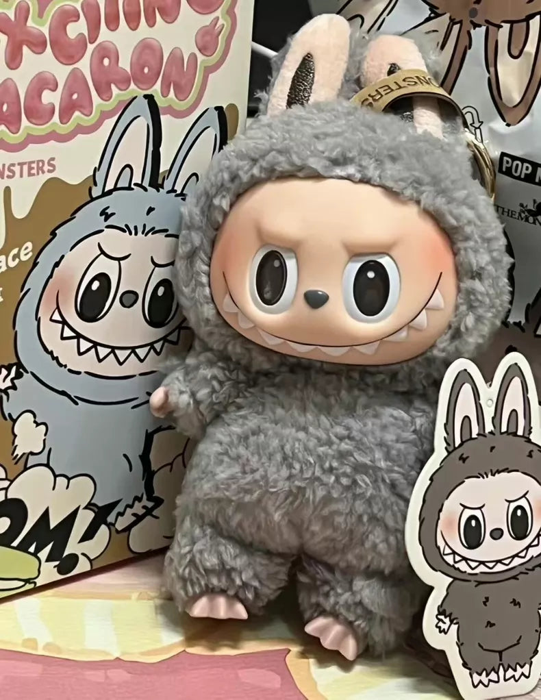 The Labubu “Sesame Bean” Plush Keychain – a POP MART collectible by Kasing Lung – features a standing grey bunny with big eyes, toothy smile, matching illustrated packaging, and comes with a sticker.