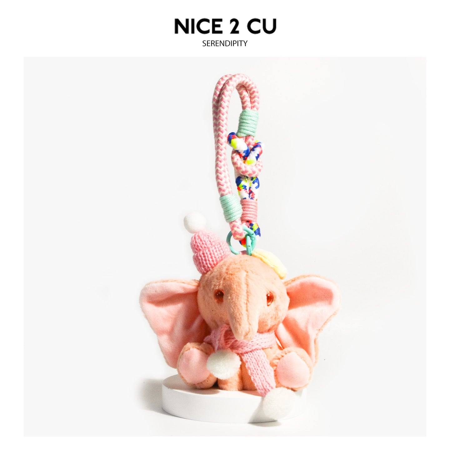 Pink plush elephant charm with pink knitted scarf, white pompom details, and mint-green wrapped clip strap