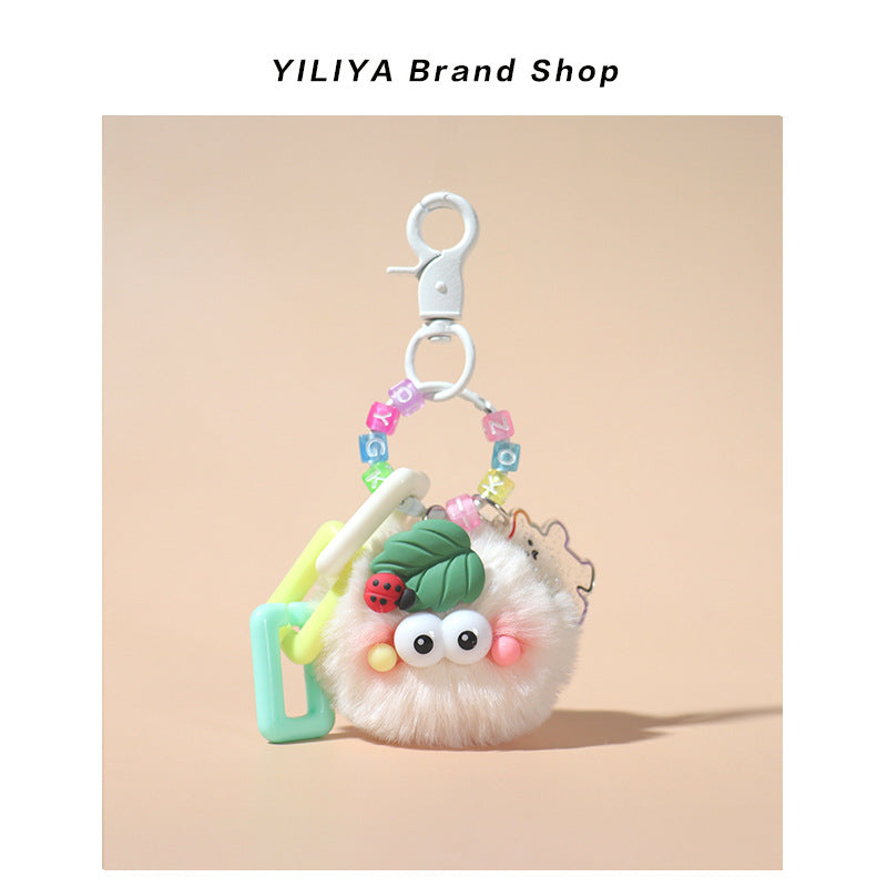 Cream white fluffy pom-pom charm with small clip hardware, pastel square beads, glittery flower outline, and ladybug leaf top