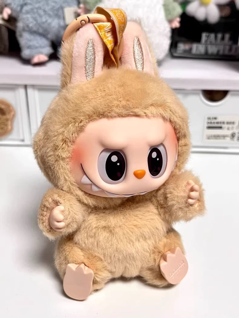 The Labubu “Baba” Plush Keychain – Have a Seat Series Brown Bunny by POP MART features a plush toy with a round face, big eyes, and cheeky grin in a fuzzy brown bunny suit, sitting on a white surface.