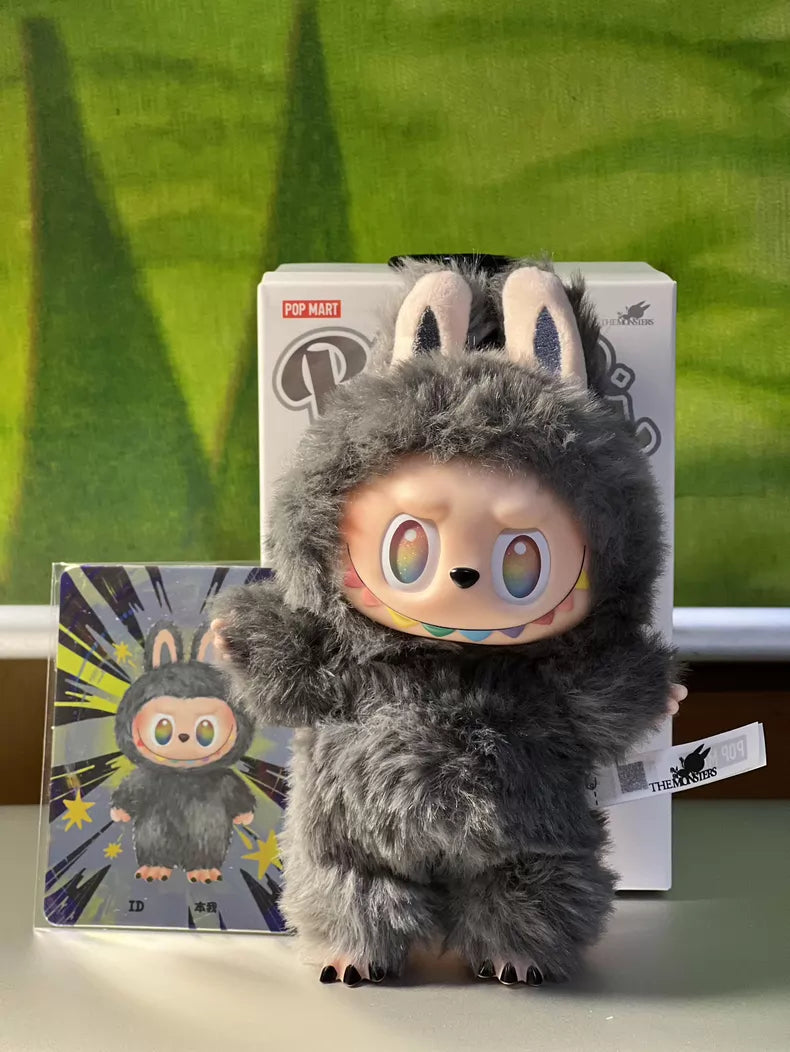 The POP MART Labubu “Secret Edition” Plush Keychain from The Monsters “Big Into Energy” Series features a gray bunny design and comes with packaging and a matching illustrated card, shown against a green background.