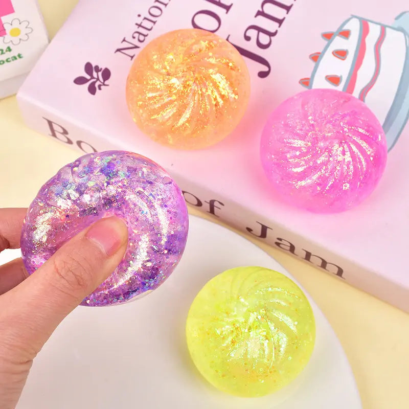 Four ZoDoll Glitter Squishy Dumpling Sensory Fidget Toys with Steamer are shown—one being squeezed by hand, others near a book and plate—perfect for stress relief, sensory play, and relaxation.