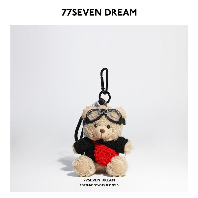 Beige plush teddy bear keychain in black knit sweater with red knitted front pouch accent and aviator goggles