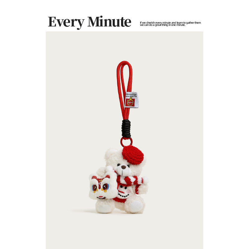 White plush teddy bear charm with red hat, striped scarf, red sweater, and white lion-dance face accessory on side