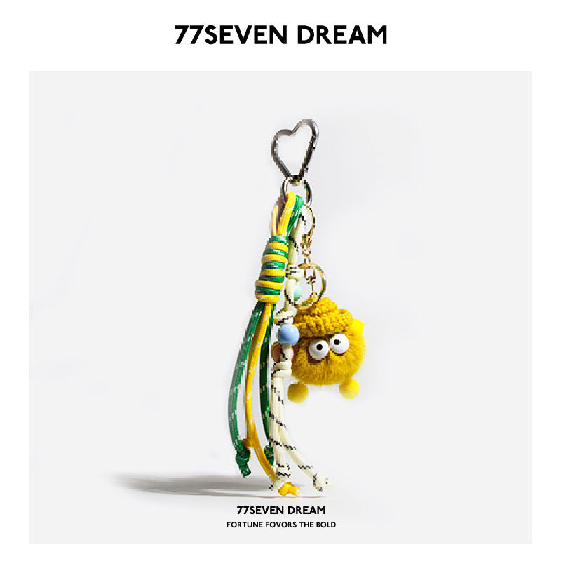 Yellow fluffy plush monster bag charm with heart clip and green-white braided cord lanyard