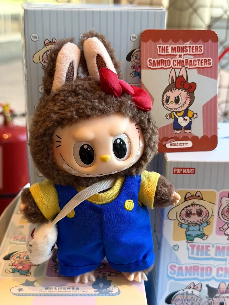 The POP MART LABUBU Hello Kitty and Friends Series Secret Edition Plush Pendant Figure, dressed in a brown bunny hood, blue overalls, and yellow shirt, stands beside a collectible The Monsters x Sanrio Characters card.