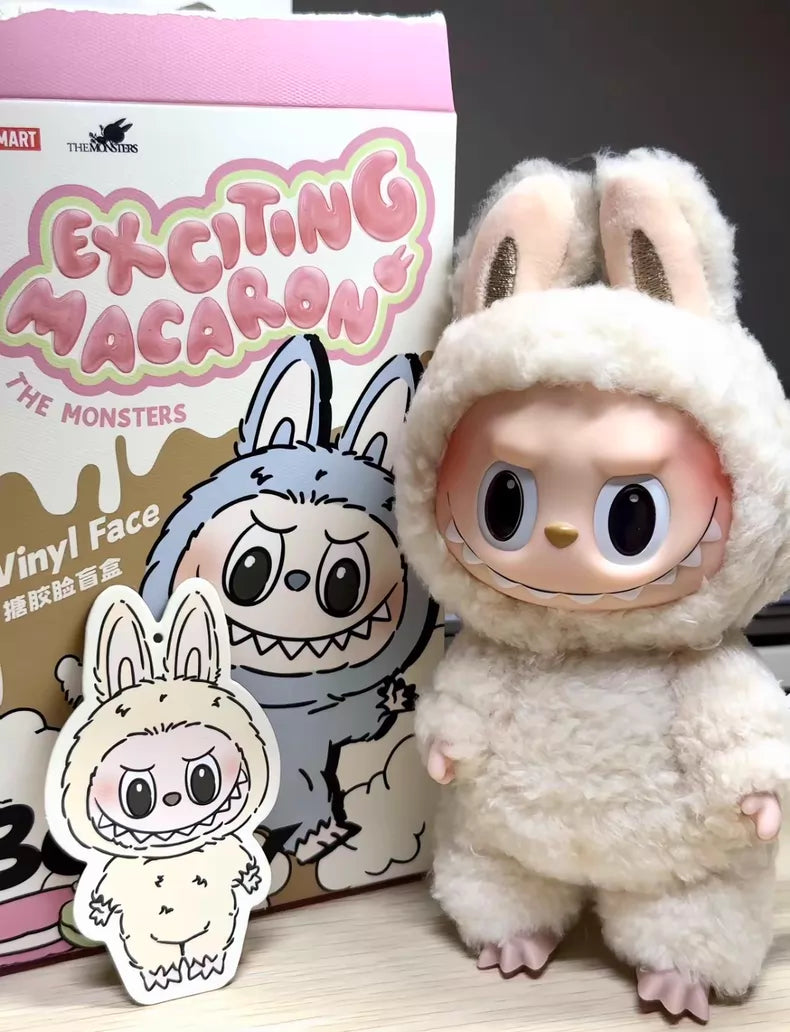 The Labubu “Soymilk” Plush Keychain – Pop Mart The Monsters Beige Bunny Doll by POP MART stands beside its illustrated cutout, with a vibrant Pop Mart box showing the same character in the background.