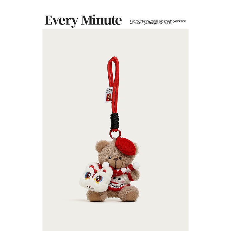 Brown plush teddy bear charm with red beret, striped scarf, red sweater, and white lion-dance face accessory on side