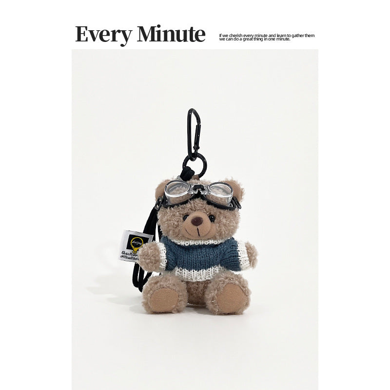 Brown bear plush keychain charm wearing aviator goggles and a blue-and-white knit sweater with black carabiner clip