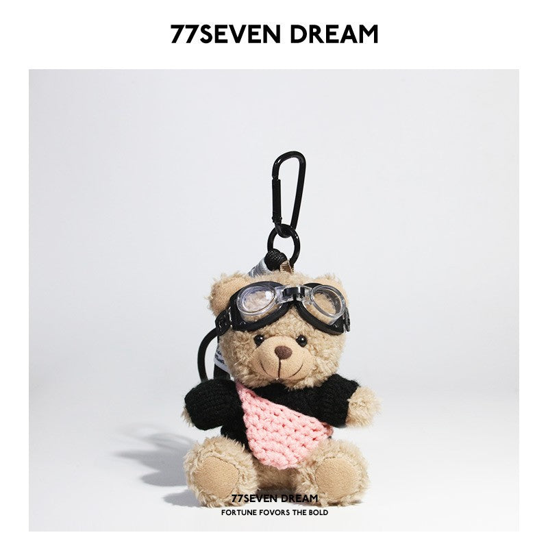 Beige plush teddy bear keychain in black knit sweater with pink knitted front pouch accent and aviator goggles