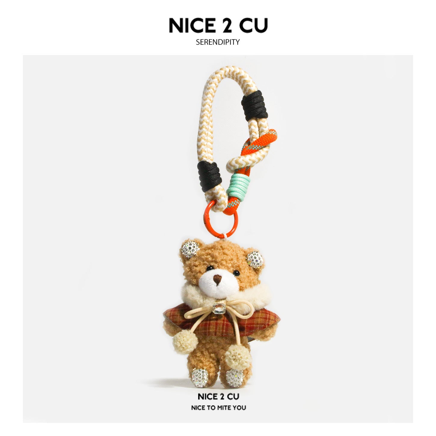 Tan plush teddy bear bag charm wearing a plaid cape with bow and pom-pom ends, attached to a braided cord strap