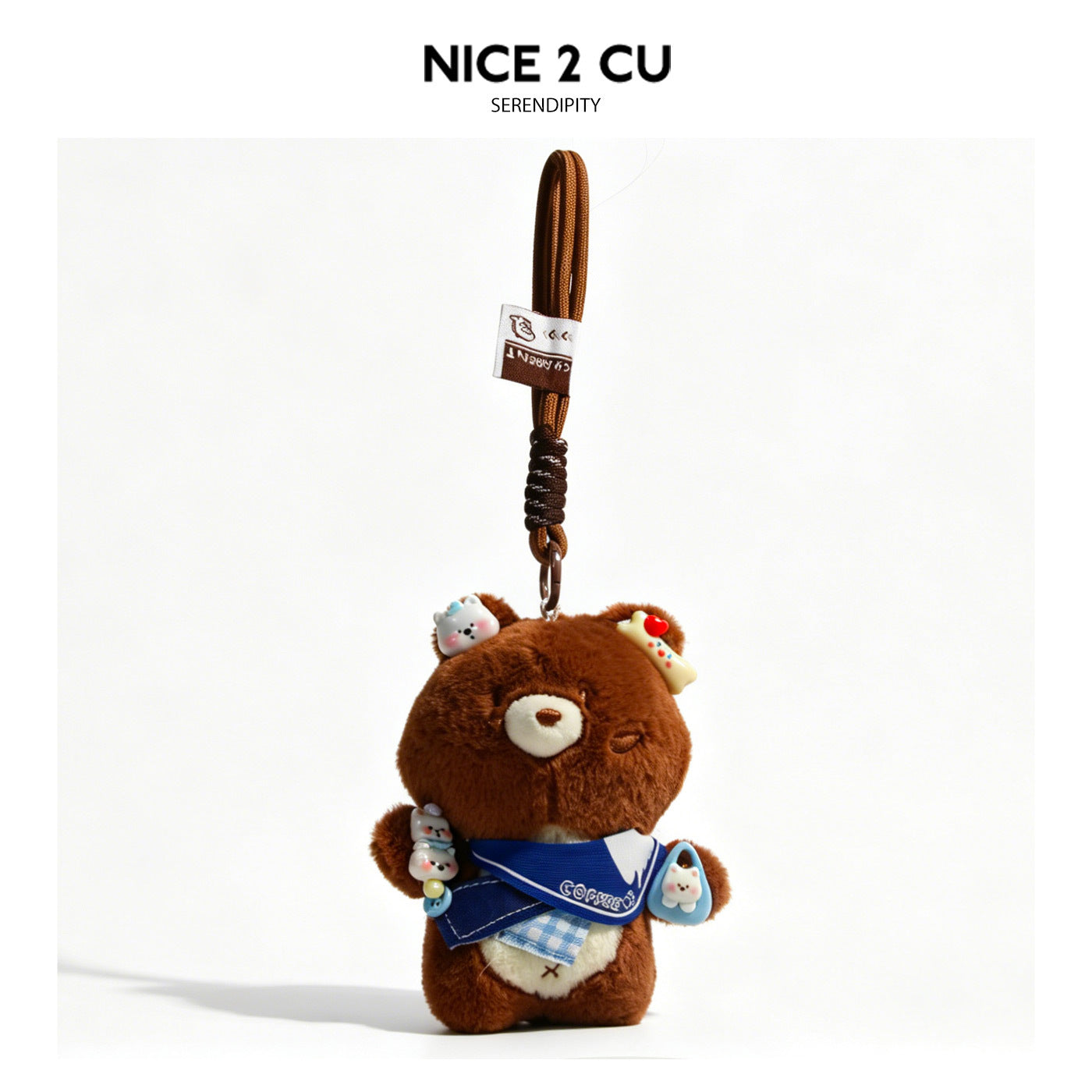 Brown plush bear charm wearing a denim-blue bib with small decorative accents, attached to a brown braided cord strap