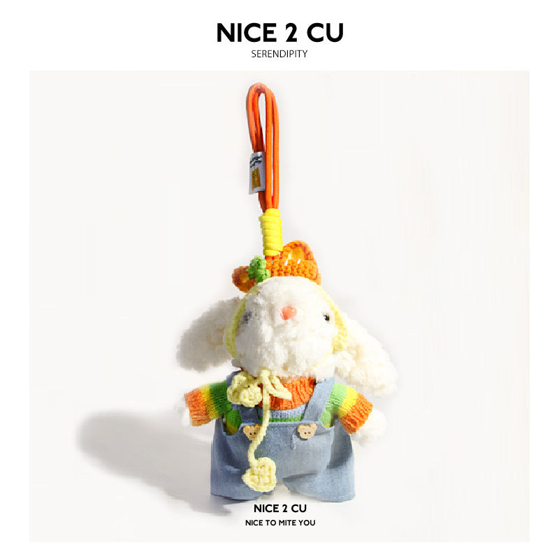 White plush rabbit bag charm wearing rainbow-striped knit sweater and light blue denim overalls with carrot hat and clip-on h