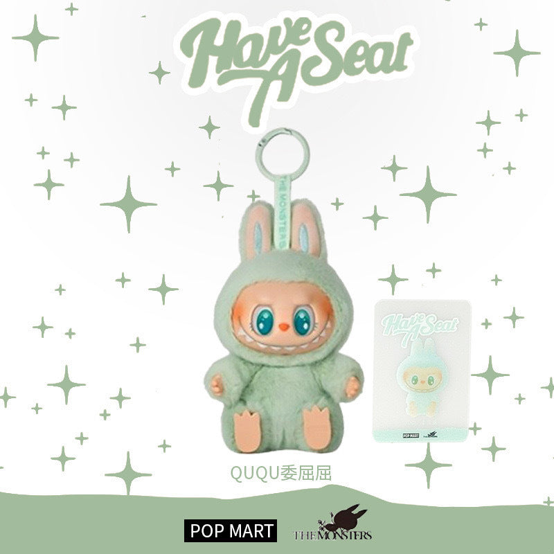 The Labubu “Ququ” Plush Keychain – Have a Seat Series Green Bunny by POP MART features Labubu in a green bunny suit with a matching card, set on a white background decorated with green stars and "Have A Seat" text above.