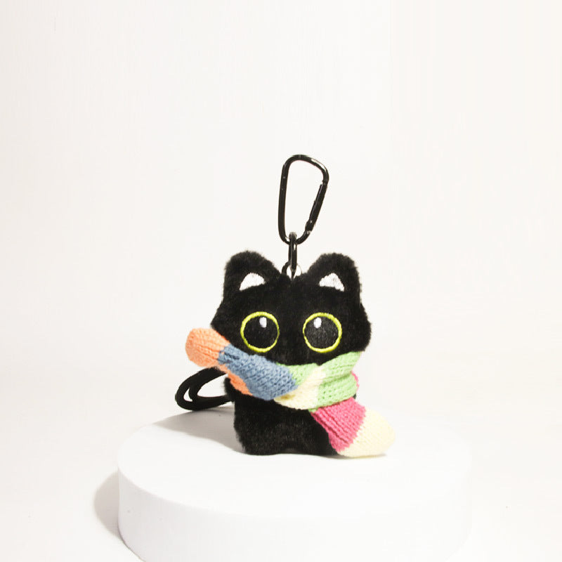 Black cat plush keychain with large yellow-outlined eyes wearing a multicolor rainbow-striped scarf