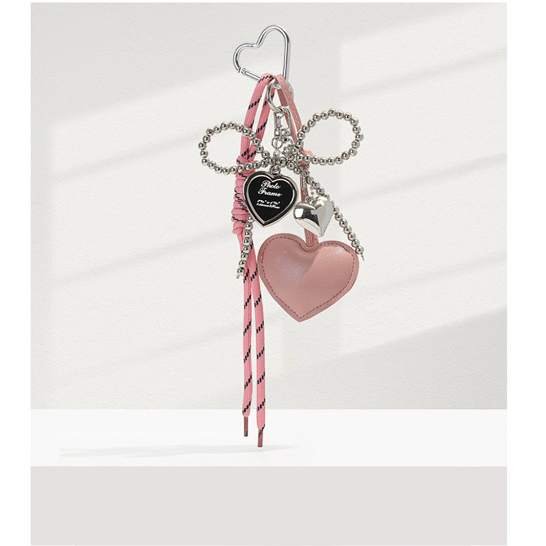 Pink faux-leather heart bag charm with pearl bead bow, silver accents, and pink striped ribbon tassel