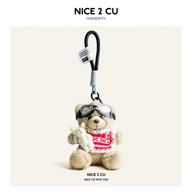 Beige plush teddy bear keychain in red-and-white striped knit sweater with aviator goggles, holding a white rabbit