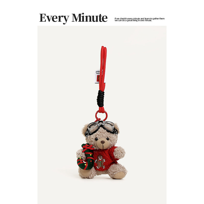 Beige plush teddy bear hanging charm in a red gingerbread man sweater holding a striped candy cane accessory, with red strap 