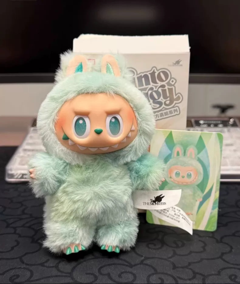 A POP MART Labubu “Serenity” Plush Keychain from The Monsters “Big Into Energy” Series, Mint Bunny Bag Charm, stands before its box and matching illustrated card on a black surface.