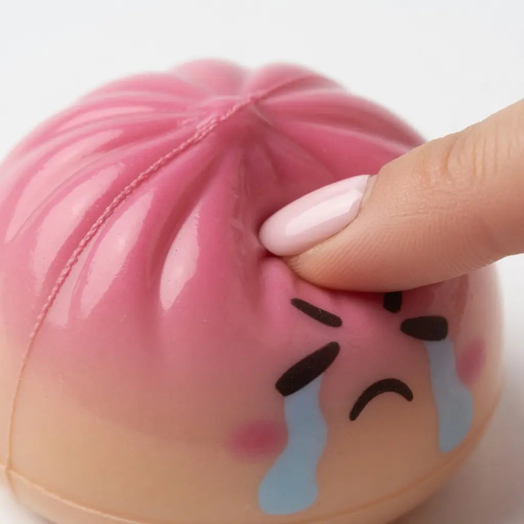 A hand squeezes the ZoDoll Giant Emoji Squishy Dumpling Bun Sensory Fidget Toy with Steamer—featuring a cute, expressive face—perfect for stress relief and sensory fun for kids and adults.