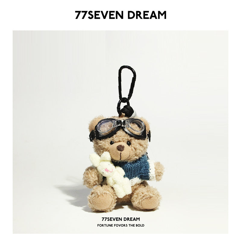 Tan bear plush keychain wearing blue-and-white knit sweater and goggles while holding a small white rabbit plush