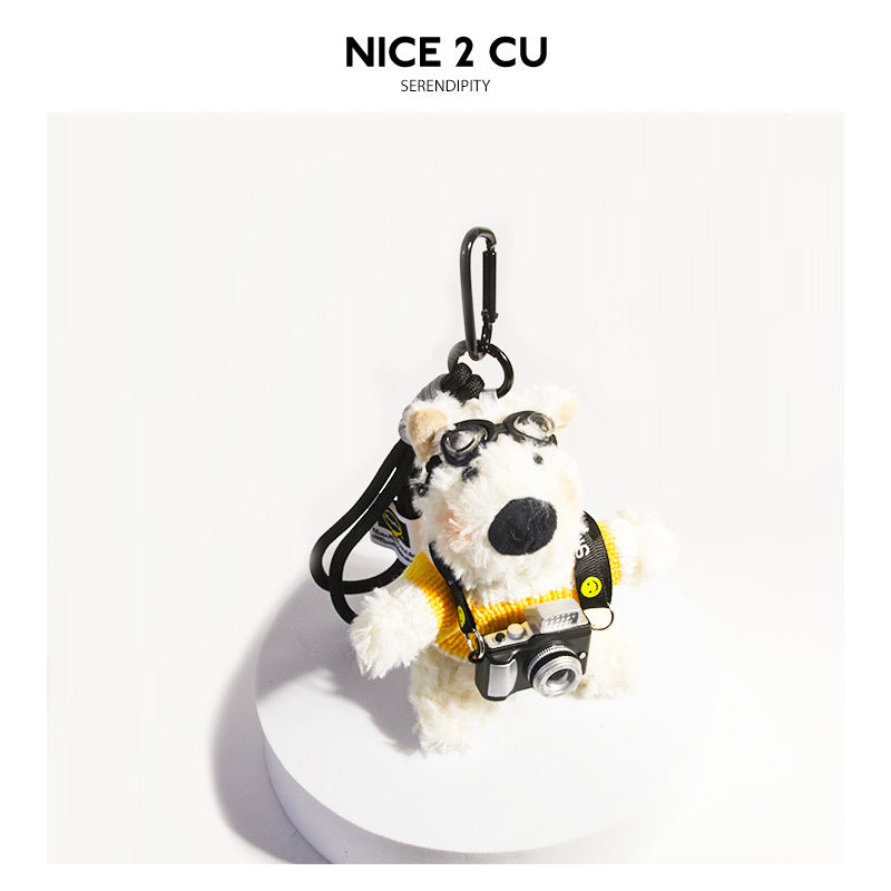 Fluffy white dog plush keychain wearing a yellow sweater, aviator goggles, and a miniature camera with carabiner clip