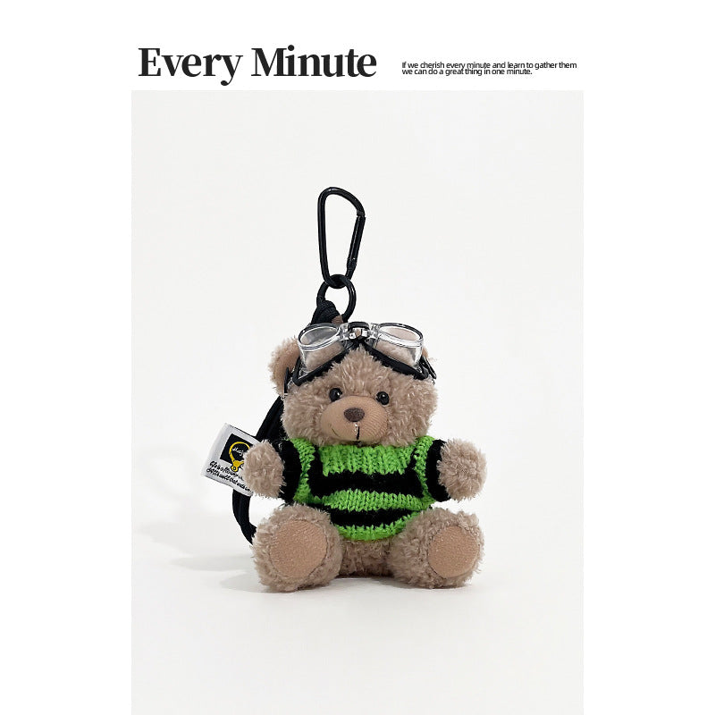 Brown bear plush keychain charm wearing aviator goggles and a black-and-green striped knit sweater with black carabiner clip