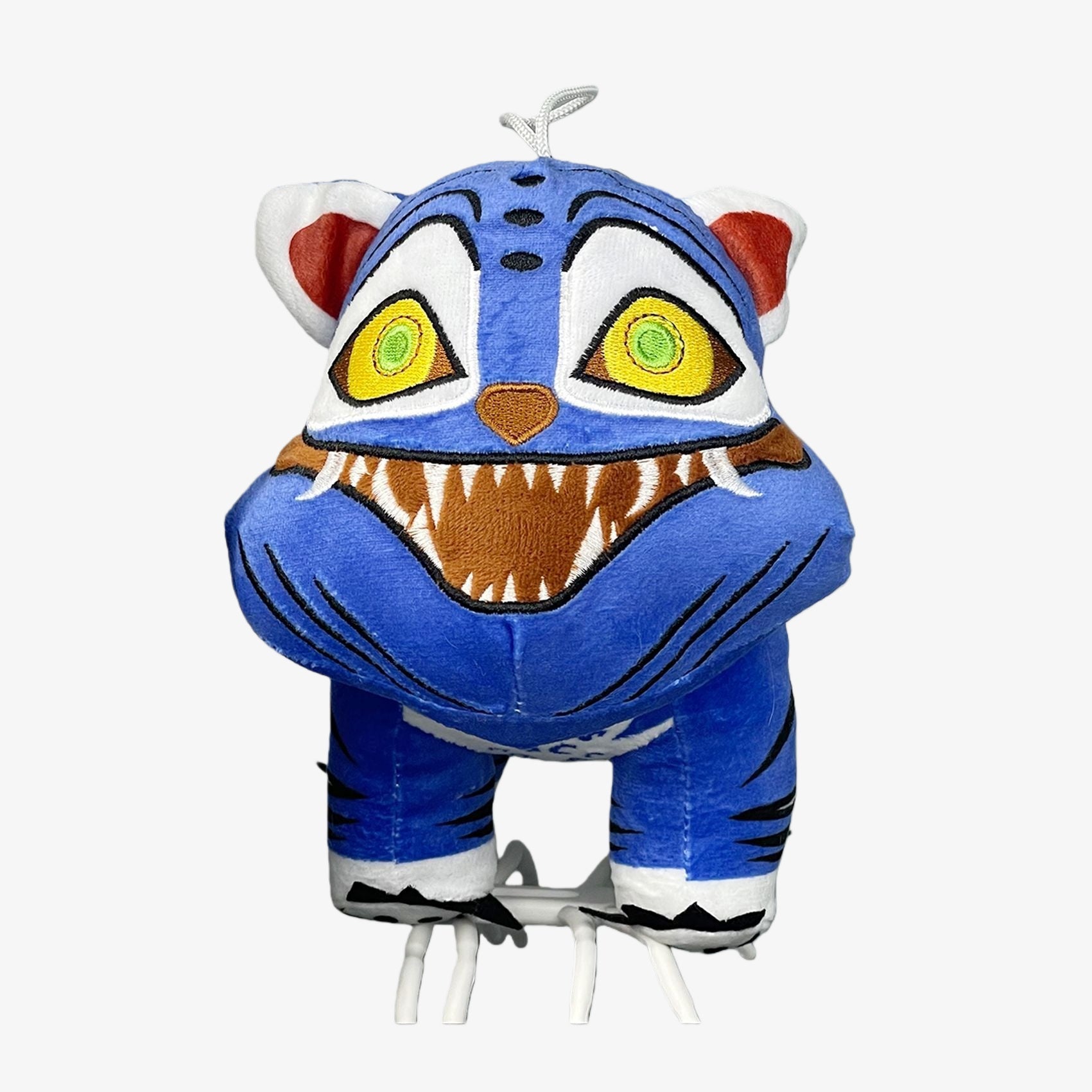 The Demon Hunters Monster Plush Doll is a 10-inch blue tiger creature with yellow eyes, sharp-toothed grin, and black stripes. This soft stuffed toy features a hanging loop—perfect for any anime merchandise collection.