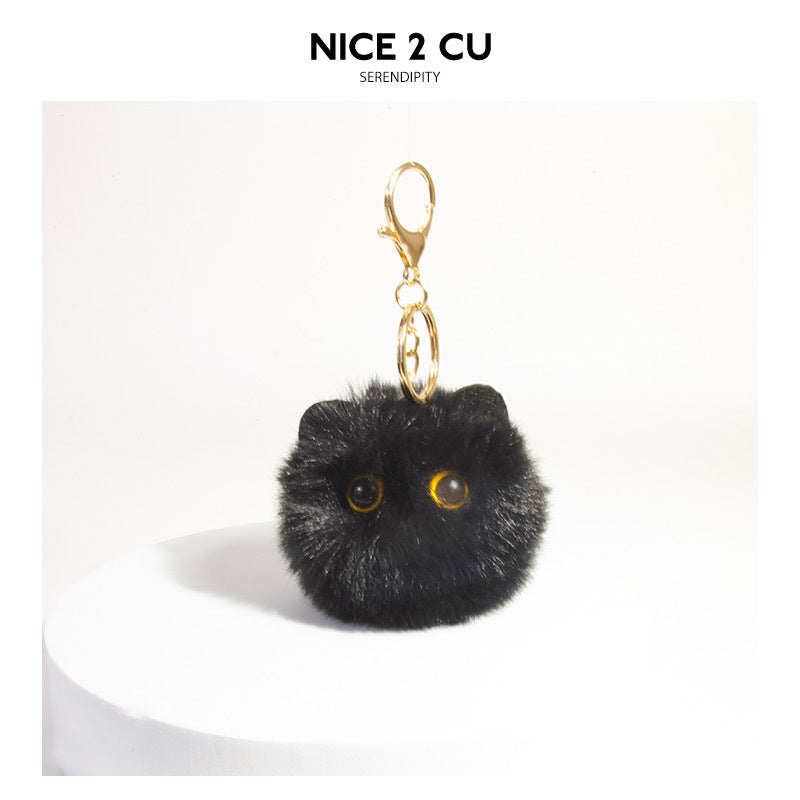 Black fluffy pom-pom cat face keychain charm with yellow eyes and gold-tone lobster clasp