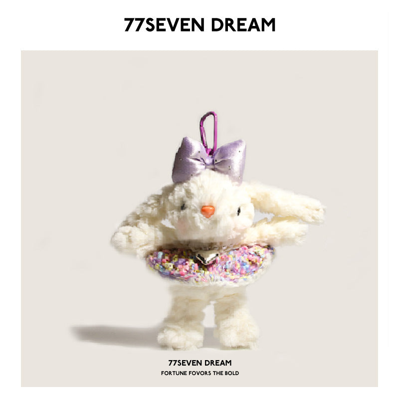 White bunny plush charm with purple bow and purple-toned knit dress