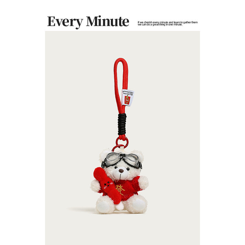 White plush teddy bear keychain charm wearing red sweater with gold character, aviator goggles, holding tanghulu skewer, red 