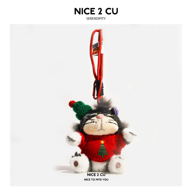 Grumpy black and white cat plush charm wearing a red knitted Christmas tree sweater and green beanie with red pom-pom, attach