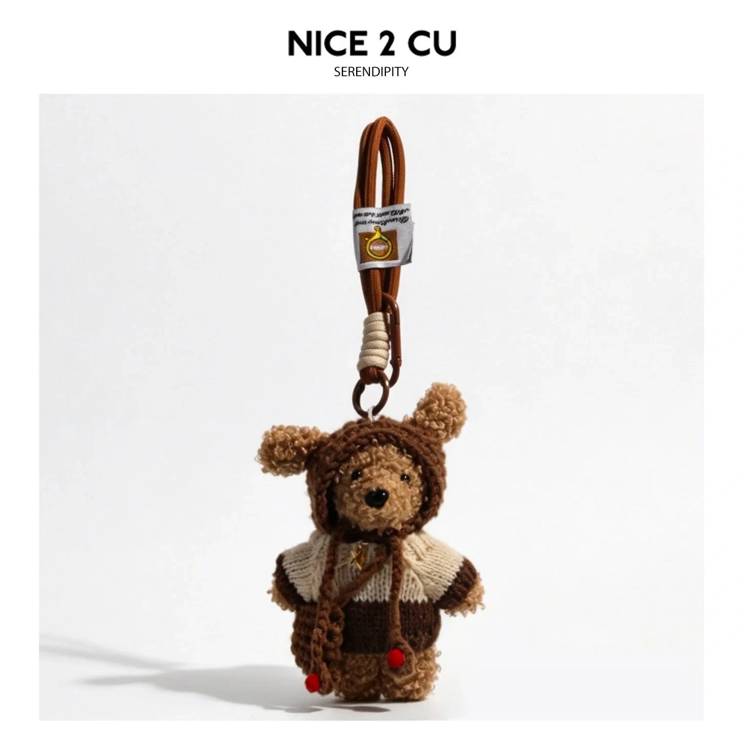 Curly plush puppy bag charm wearing a cream and dark brown color-block knitted sweater with a floppy-eared hood and braided