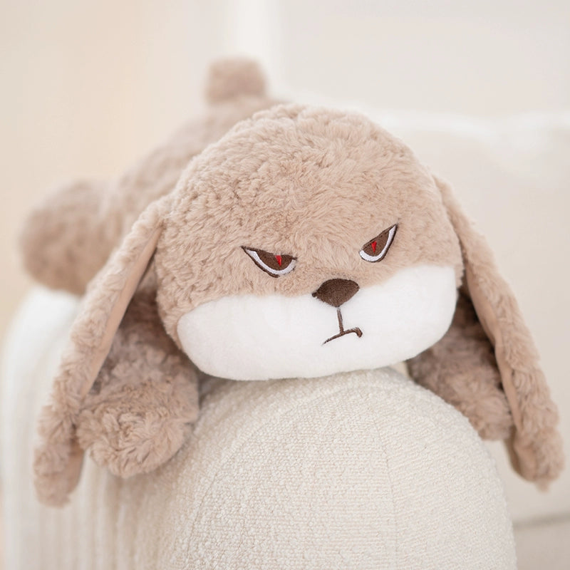 The ZEIO Lying Bunny Plush Toy 50cm is a soft, flat rabbit stuffed animal with light brown fur, floppy ears, and an angry face, resting like a plush pillow on a white sofa.