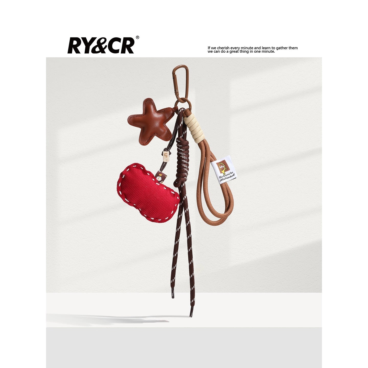 Red apple-shaped fabric charm with tan star accent on brown braided lanyard and carabiner clip